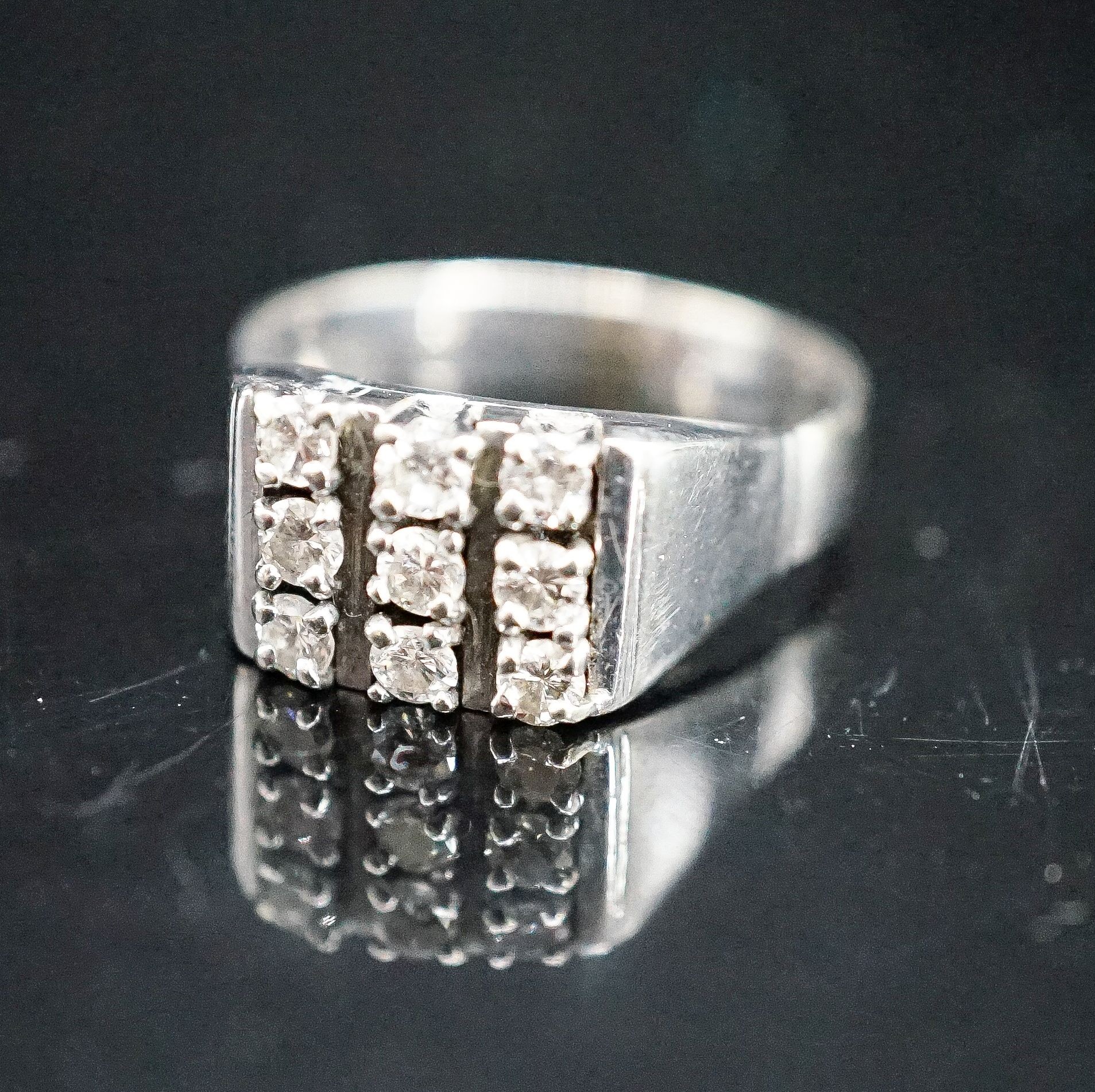 A 750 white metal and nine stone diamond set tablet ring, size S/T, gross 7.6 grams.